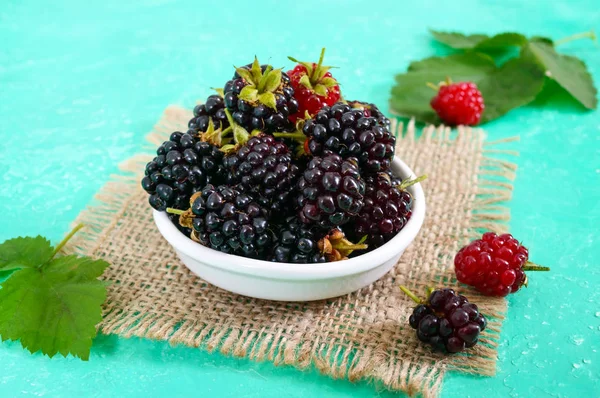 Parlak bir arka plan üzerinde seramik bir kase lezzetli olgun böğürtlen.