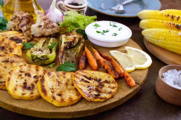 Izgara sebze, taze otlar, sos bir ahşap tepsi üzerinde. Sağlıklı gıda. Lezzetli bir meze.