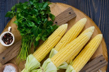 Genç Mısır koçanı yaprakları, baharat, otlar, deniz tuzu bir ahşap tepsi ile. Üstten görünüm.