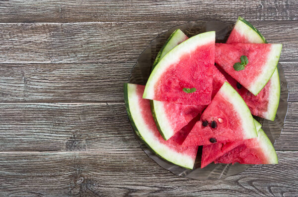 Кусочки спелого арбуза на тарелке на деревянном столе. Вид сверху
.
