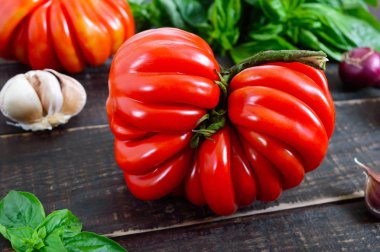 Büyük Olgun kırmızı domates fesleğen ahşap bir tablo ile. İtalyan domates çeşitli.