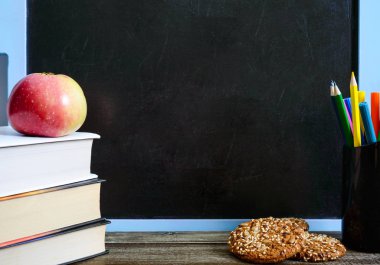 Okul hazırlıkları eğitim kavramı. Kitaplar, yararlı, tam tahıllı kurabiye ve elma yazı tahtası önünde sınıf masada okul malzemeleri. Uzay kopyalayın. Sağlıklı ve apple ile akıllı olacak tam tahıllı çerezleri her gün okula geri ne zaman