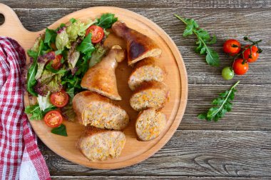 Ahşap arka plan üzerinde taze sebze salatası ile lezzetli doldurulmuş tavuk budu. Rulo tavuk ve sebze ile. Üstten görünüm.