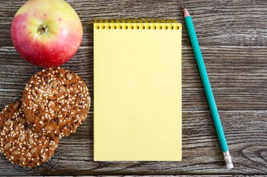 Sağlıklı beslenme kavramı. Elma, tahıl çerezleri bir yer notlarınızın ortasında ahşap bir arka plan üzerinde. Üstten görünüm.