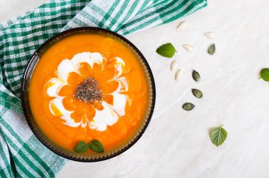 Hafif bir arka plan üzerinde siyah cam kapta krem ve chia tohumu ile hassas kabak püresi. Üstten görünüm.