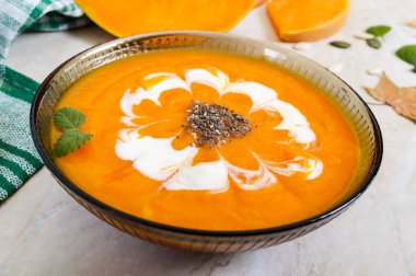 Hafif bir arka plan üzerinde siyah cam kapta krem ve chia tohumu ile hassas kabak püresi.