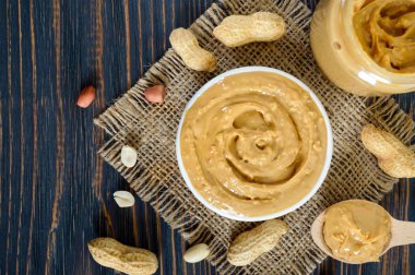 Ahşap bir masa üzerinde bir seramik kase fıstık ezmesi. Amerikan mutfağının geleneksel bir ürünüdür. Üstten görünüm.