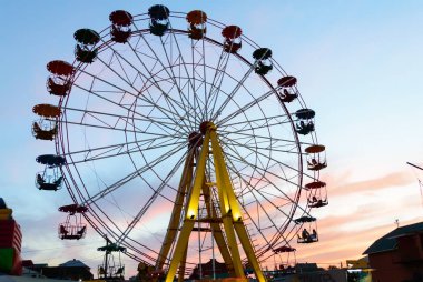 Gün batımını arka plan üzerinde eğlence parkı. Dönme dolap