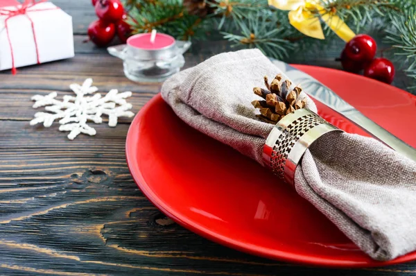 圣诞餐桌设置 红色盘子 餐巾纸 礼物树枝上的圣诞树上的一个黑暗的木制的背景 复制空间 圣诞新年假期背景 — 图库照片