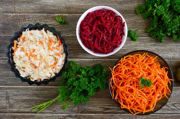 Salads from fresh vegetables: cabbage, carrots, beets. Korean spicy salads in bowls on a wooden table. Top view. Vitamin menu. Vegan cuisine.