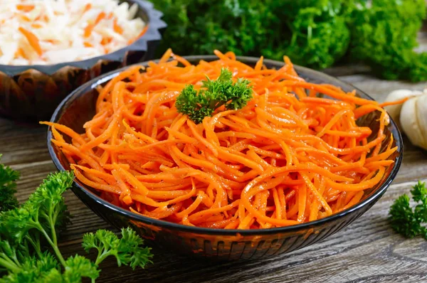 Salads from fresh carrots. Korean spicy vegetables salad in bowl on a wooden table. Vitamin menu. Vegan cuisine.