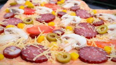 Güzel pizza pişirme için hazır bir kalp şeklinde. Mantar, salam, sucuk, zeytin, Mısır fırın tepsisindeki pizza.