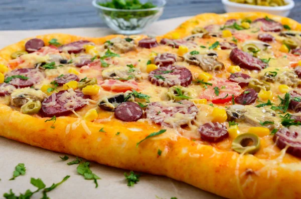 Tasty pizza in a heart shape with mushrooms, salami, pepperoni, olives, corn. Close up