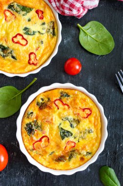 Frittata taze sebze ve ıspanak ile. Siyah zemin seramik formlarda İtalyan omleti. Üstten görünüm.