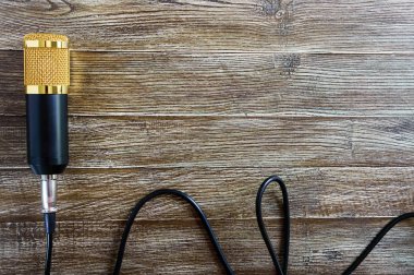 Altın mikrofon kablosu ile ahşap bir masa üzerinde kopya alanı ile yatıyor. Müzikal tema. Düz yatıyordu. Üstten görünüm.