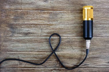 Altın mikrofon kablosu ile ahşap bir masa üzerinde kopya alanı ile yatıyor. Müzikal tema. Düz yatıyordu. Üstten görünüm.