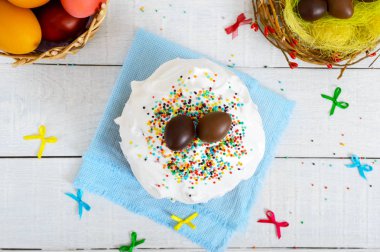 Geleneksel Paskalya kek - kulich ve çikolata yumurta ahşap beyaz zemin üzerinde bir yuva. Tatlı ekmek beze dekore edilmiştir. Üstten görünüm. Paskalya tema.