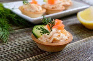 Krem peynir ve ahşap arka plan üzerinde tuzlanmış somon ile tartlets. Bir parti için lezzetli hafif aperatif. Parmak gıda.
