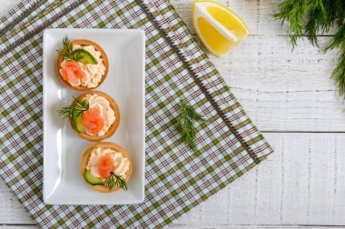 Krem peynir ve beyaz tabakta tuzlanmış somon ile tartlets. Bir parti için lezzetli hafif aperatif. Parmak gıda. Üstten Görünüm, düz yatıyordu.
