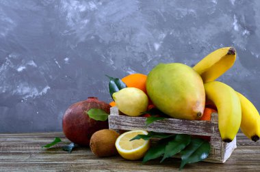 Masada mezarda egzotik meyve (muz, portakal, kivi, nar, mango, guava, limon) yığını.