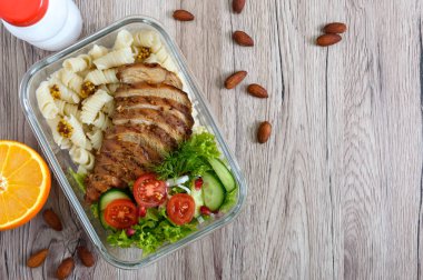 Beslenme çantası: fırında tavuk göğsü ve ahşap arka plan üzerinde salata ile rotini. Üstten Görünüm, düz yatıyordu. Lezzetli sağlıklı öğle yemeği. Sağlıklı beslenme kavramı.