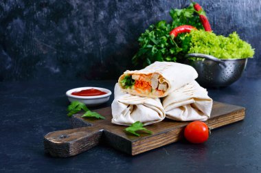 Siyah bir zemin üzerine lezzetli shawarma sandviç. Burrito ızgara tavuk ve sebze, yeşillik ile tamamladı. Fajitas, pide. Geleneksel Orta Doğu meze. Sağlıklı gıda. Meksika mutfağı.