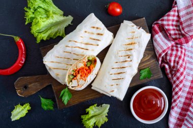 Siyah bir zemin üzerine lezzetli shawarma sandviç. Burrito ızgara tavuk ve sebze, yeşillik ile tamamladı. Fajitas, pide. Geleneksel Orta Doğu meze. Sağlıklı gıda. Üstten Görünüm, düz yatıyordu