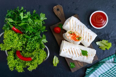 Siyah bir zemin üzerine lezzetli shawarma sandviç. Burrito ızgara tavuk ve sebze, yeşillik ile tamamladı. Fajitas, pide. Geleneksel Orta Doğu meze. Sağlıklı gıda. Üstten Görünüm, düz yatıyordu