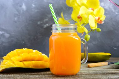 Mango smoothie bir cam ve ahşap arka plan üzerinde taze mango. Mango shake. Tropikal meyve kavramı.