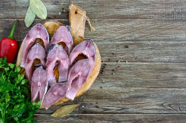Bir masada ahşap bir kesme tahtasında çiğ biftekler Nehir balığı. Yemek pişirmek için hazır. Üst görünüm.