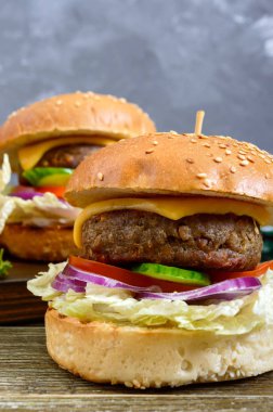 Sulu cutlet ile hamburgerler, taze sebzeler, ahşap bir masada susam ile gevrek topuz. Close. Geleneksel Fast Food.