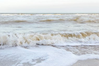 Kıyıya dalgalar. Güneş ışığı ile kumlu bir plajda deniz dalgası yakın.