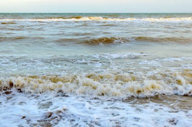 Kıyıya dalgalar. Güneş ışığı ile kumlu bir plajda deniz dalgası yakın.