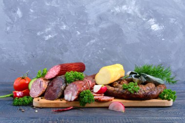 Birçok çeşit sosis, füme peynir, tahta bir arka plan üzerinde taze sebze. Tatil ürünleri.