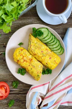 Omlet, tahta bir masada sebze ve otlar ile yumurta rulo. Lezzetli sağlıklı kahvaltı. Üstte görüntü.