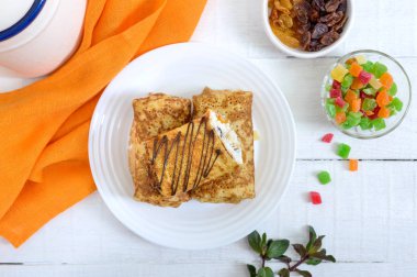 Beyaz ahşap arka plan üzerinde süzme peynir ve kuru üzüm ile lezzetli hassas krep. Sağlıklı kahvaltı. Üst görünüm