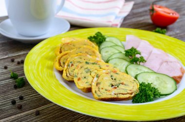 Omlet, jambon ve tahta bir masa üzerinde taze salatalık ile yumurta rulo. Lezzetli sağlıklı kahvaltı.