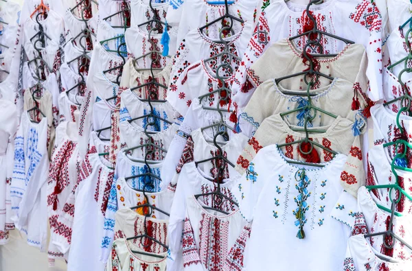 Ukrainian embroidered shirts, national handmade clothes. Traditional linen shirt with embroidered flowers and ornaments at local market at state fair.  Fair - an exhibition of folk craftsmen open air.