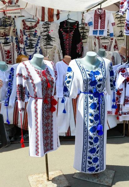 Ukrainian embroidered shirts, national handmade clothes. Traditional linen shirt with embroidered flowers and ornaments at local market at state fair.  Fair - an exhibition of folk craftsmen open air.