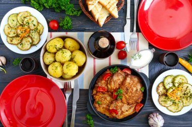 Haşlanmış genç patates, kızarmış kabak dilimleri, tahta bir masada şnitzeller. Üst te. Aile yemeği, öğle yemeği için servis edilen masa. Rustik stil