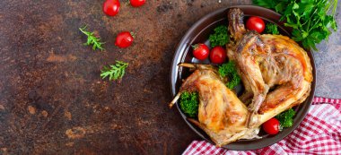 Bir tabaktabakta yeşillik ve domates ile bütün pişmiş tavşan. Lezzetli diyet eti. Üst görünüm, düz yatıyordu. Afiş