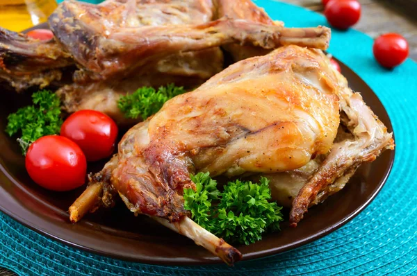 Bir tabaktabakta yeşillik ve domates ile bütün pişmiş tavşan. Lezzetli diyet et.