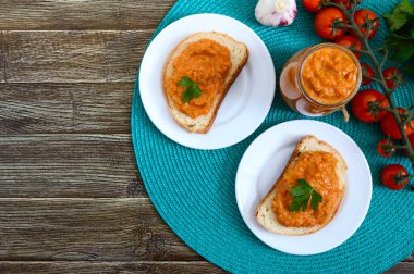 Bir kavanozda lezzetli kabak havyar ve masada beyaz ekmek dilimleri yayıldı. Kabak, sarımsak, havuç, domates soslu ev yapımı havyar. Vegan mutfağı. Üst teki görüş. Düz yatıyordu