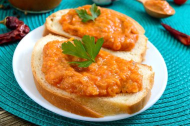 Bir kavanozda lezzetli kabak havyar ve masada beyaz ekmek dilimleri yayıldı. Kabak, sarımsak, havuç, domates soslu ev yapımı havyar. Vegan mutfağı. Yakın çekim