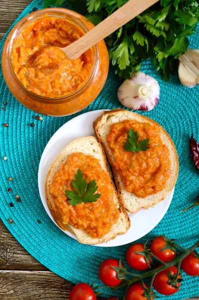 Delicious squash caviar in a jar and spread on slices of white bread on the table. Homemade caviar with zucchini, garlic, carrots, tomato sauce. Vegan cuisine. The top view. Flat lay