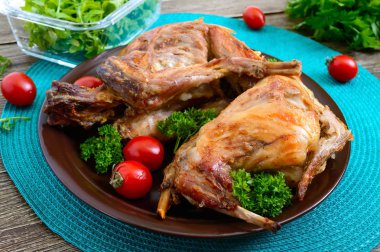 Bir tabaktabakta yeşillik ve domates ile bütün pişmiş tavşan. Lezzetli diyet et.