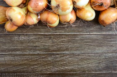 Tahta bir masada büyük bir demet soğan. Taze hasat, popüler sağlıklı sebzeler. Projeniz için boş alan. Üst görünüm, düz yatıyordu. Gıda arka plan.