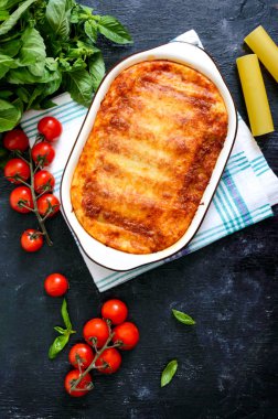 Beşamel soslu cannelloni dolması. Cannelloni makarna et, krema sosu, siyah bir arka plan üzerinde peynir ile pişmiş. Üst görünüm, düz yatıyordu.