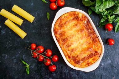 Beşamel soslu cannelloni dolması. Cannelloni makarna et, krema sosu, siyah bir arka plan üzerinde peynir ile pişmiş. Üst görünüm, düz yatıyordu.