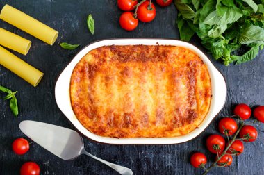 Beşamel soslu cannelloni dolması. Cannelloni makarna et, krema sosu, siyah bir arka plan üzerinde peynir ile pişmiş. Üst görünüm, düz yatıyordu.